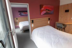 a bedroom with two beds and a mirror in it at L'Orée des Sources in Volvic