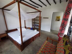 a bedroom with a canopy bed and a couch at EAST SANDBANK apartment eco-friendly Nungwi airport road in Nungwi