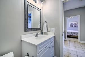 Un baño blanco con lavabo y espejo. en Spacious Southport Condo with Balcony!, en Southport 27 fotos más