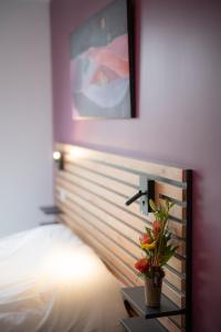 - une chambre avec un lit et une plante sur le mur dans l'établissement L'Orée des Sources, à Volvic