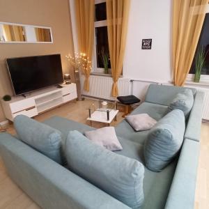 uma sala de estar com um sofá azul e uma televisão em Schönes Ferien-Appartement für bis zu 6 Personen em Halberstadt