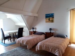 um quarto com 2 camas, uma mesa e cadeiras em Chambres d'Hôtes L'Insulaire em Saint-Denis-dʼOléron