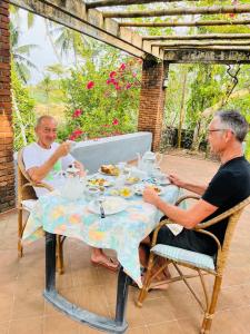 Dois homens sentados à mesa a comer. em Swarnapaya résidence em Bentota