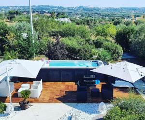 a swimming pool with two umbrellas and chairs next to at Villa Nirya - Trulli Resort & Pool by TrulloVista in Martina Franca