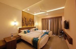 a hotel room with two beds and a flat screen tv at Golden Fruits Business Suites in Chennai
