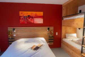 sypialnia z 2 łóżkami piętrowymi i czerwoną ścianą w obiekcie L'Orée des Sources w mieście Volvic