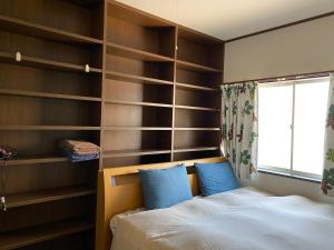 a bedroom with wooden shelves and a bed with blue pillows at 山科車站yamashina in Kyoto