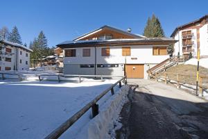 a white building with a fence in the snow at Nuovo Appartamento Super Vista a Campiglio Parking Privato in Madonna di Campiglio