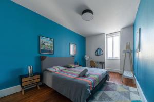 - une chambre bleue avec un lit et un mur bleu dans l'établissement Le 482 - Grand Appartement design & Confort - 4 chambres, à Vichy