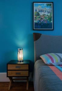 um quarto azul com uma cama e uma mesa de cabeceira com um candeeiro em Le 482 - Grand Appartement design & Confort - 4 chambres em Vichy