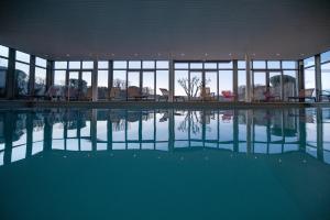 an empty swimming pool in a building with windows at Domaine Du Val in Grand-Laviers