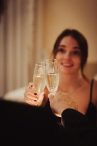 Uma mulher está a segurar duas taças de champanhe. em Hotel Trettenero em Recoaro Terme