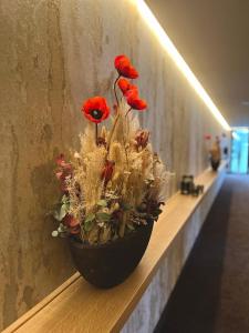un jarrón lleno de flores rojas en una pared en Hotel Le 830 Namur, en Namur