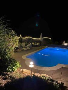 una gran piscina azul por la noche con luz en Appartement mit Alpensicht, beheiztem Pool, Garten, 