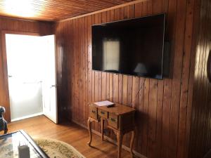 a living room with a tv on a wooden wall at BlackBeard's Retreat - Historic and Pet Friendly cottage in Kitty Hawk