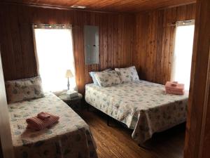 a bedroom with two beds and two windows at BlackBeard's Retreat - Historic and Pet Friendly cottage in Kitty Hawk