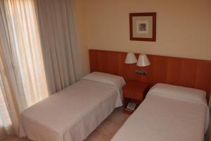 um quarto de hotel com duas camas e uma janela em Hotel del Port em L'Ametlla de Mar