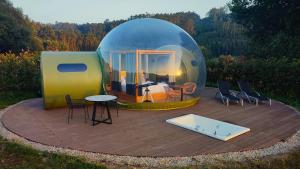 une tente en forme de dôme avec une table et des chaises sur une terrasse dans l'établissement Luzada - Glamping Burbujas Galicia, à Juances