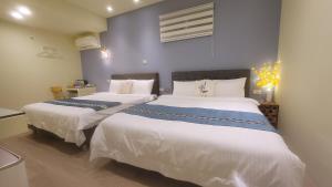 um quarto com 2 camas e lençóis brancos em 九份慕心原宿 em Jiufen