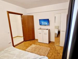 ein Schlafzimmer mit einem Bett, einem Spiegel und einem TV in der Unterkunft Belle Apartments - Bratianu in Piteşti