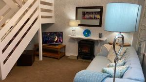 a living room with a blue couch and a television at Apple Blossom Cottage - Spring Cottages, Cheddar in Cheddar