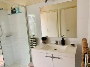 a white bathroom with a sink and a shower at Luxury Inner City Townhouse in Bendigo