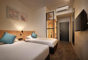 a hotel room with two beds and a television at U Hotel Penang in Bayan Lepas