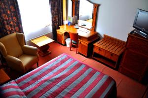 um quarto com uma cama, uma cadeira e um espelho em Hotelli Hiittenharju em Harjavalta