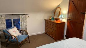 a bedroom with a chair and a dresser with a window at Apple Blossom Cottage - Spring Cottages, Cheddar in Cheddar