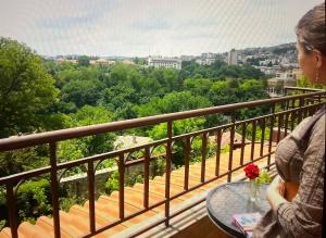 una mujer sentada en una mesa sobre un balcón en HOTEL BOLYARI en Veliko Tŭrnovo