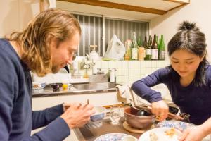 Ein Mann und eine Frau bereiten Essen in einer Küche vor. in der Unterkunft Live here like local Japanese do in Kirishima