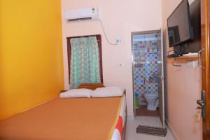 a small room with a bed and a bathroom at Farmdean Resort in Kanyakumari