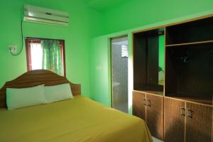 a green bedroom with a bed and a television at Farmdean Resort in Kanyakumari