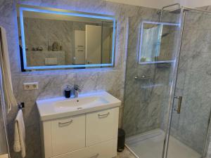 ein Bad mit einem Waschbecken und einer Dusche mit einem Spiegel in der Unterkunft Lüttje Huus Frieda mit Strandkorb am Strand von Mai bis September in Cuxhaven
