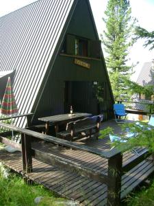 a green building with a table and a bench on a deck at Baita Giggia sulle piste - Cavalese in Trentino Alto Adige cottage chalet in Cavalese