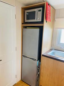 eine kleine Küche mit einem Kühlschrank und einer Mikrowelle in der Unterkunft High Tide in Burmarsh