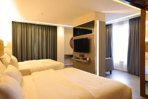 um quarto de hotel com duas camas e uma televisão de ecrã plano em Hotel The Sea View, Mangalore em Mangalore