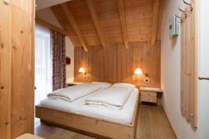 - une chambre avec un lit dans une pièce dotée de murs en bois dans l'établissement Residence Mugun, à Corvara in Badia