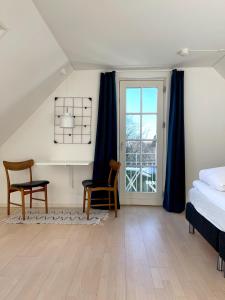 a bedroom with a bed and a desk and a window at Kirsebærkroen - The Inn Between in Præstø