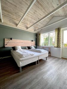 a bedroom with a large bed with a wooden ceiling at Kirsebærkroen - The Inn Between in Præstø