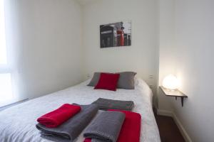 een wit bed met rode en grijze handdoeken erop bij Apartment Livemálaga Victoria in Málaga