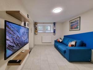 a living room with a blue couch and a large screen tv at Travel Homes - Underground, F1 chic et rénové in Mulhouse