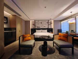 um quarto com uma cama, 2 cadeiras e uma secretária em Arthur Hotel Luogang Guangzhou em Guangzhou