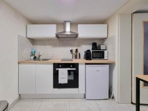 a kitchen with white cabinets and a black appliance at Travel Homes - Underground, F1 chic et rénové in Mulhouse