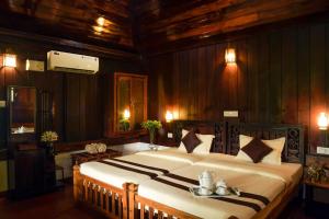 a bedroom with a large bed and wooden walls at StayVista at La Riva Heritage Villa with Bicycle in Alleppey