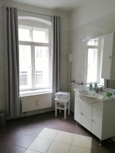 ein weißes Bad mit einem Waschbecken und einem Fenster in der Unterkunft Pension Gina in Görlitz