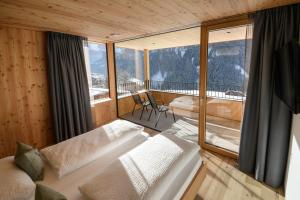 Cette chambre comprend un lit et une grande fenêtre. dans l'établissement Apartments Emilia, à Ortisei