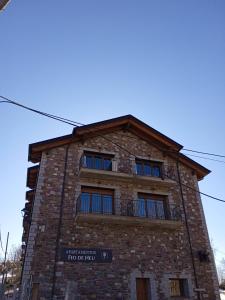 a brick building with a balcony on top of it at Apt Nuevos con caballos Fio de Neu Laspaules in Laspaúles