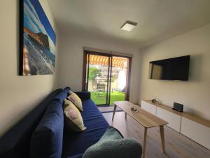 sala de estar con sofá azul y TV en Pool Sunset Apartment, en Puerto de la Cruz