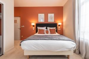 een slaapkamer met een groot bed met oranje muren bij Hôtel Échappée en Baie - Parking privé gratuit dont forfaits bornes électriques réservable in Saint-Valery-sur-Somme